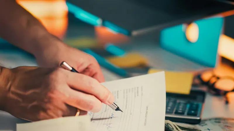 A hand signing a real estate document on a desk